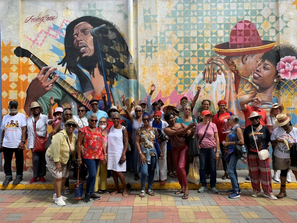 Tourists posing in front of a Kingston Creative mural in downtown Kingston.