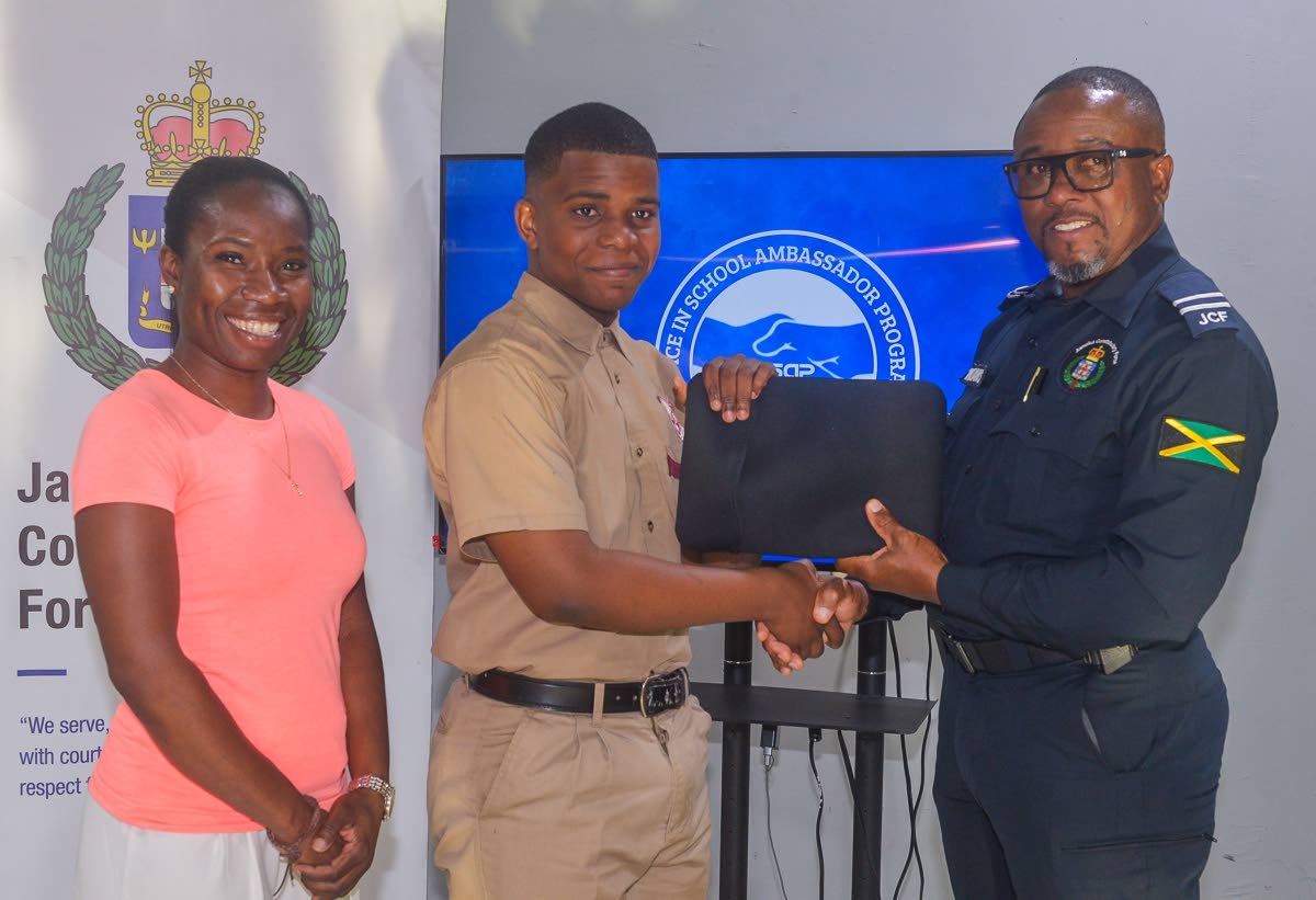 Territorial Officer in the St Catherine North Police Division, Inspector Ishmael Williams, presents student of the Spanish Town-based Eltham High School, Justine Stone , with a laptop, donated by Donique Sinclair-Chambers (left), during a recent handover c