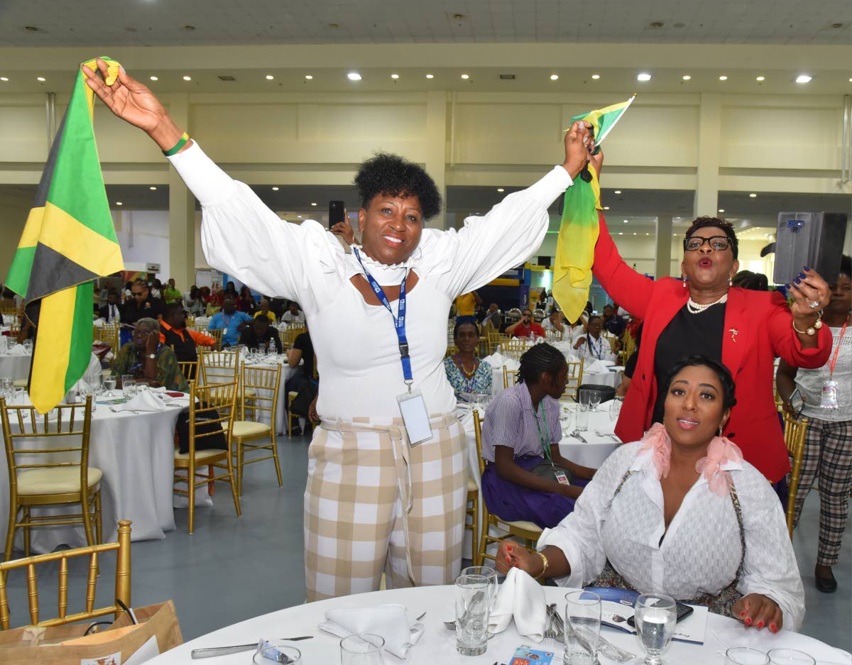 Delegates from Florida, Sandra Christie Brown (left), Georgette Stewart and Dr Rose Marie Lewis (right) waive the Jamaican flag during a presentation at the 10th Biennial Jamaica Diaspora Conference at the Montego Bay Convention Centre in Rose Hall, Monteg