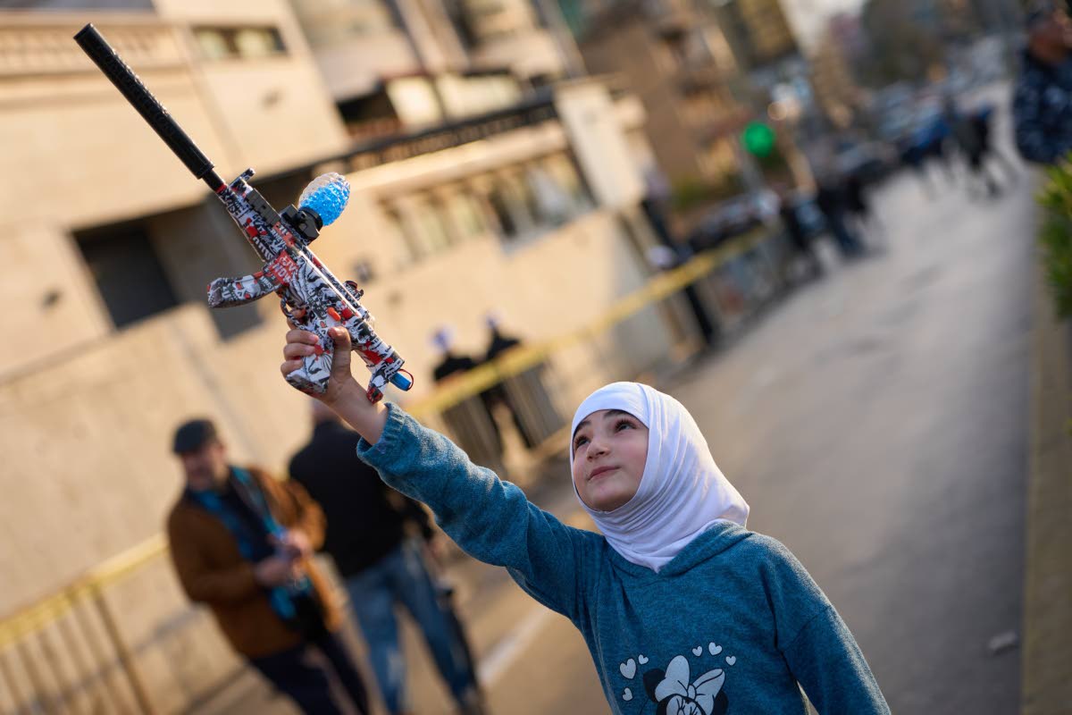 A girl holds a toy gun during a protest outside Iran’s embassy, where dozens of people gathered waving Hezbollah and Iranian flags in solidarity with the Islamic Republic, in Beirut, Lebanon, Thursday, March 26, 2026.