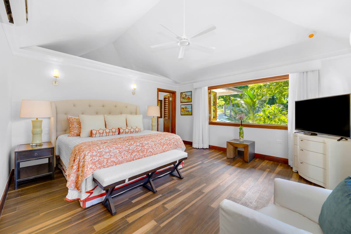 This bedroom with its upholstered, padded headboard, is fitted with large picture windows.