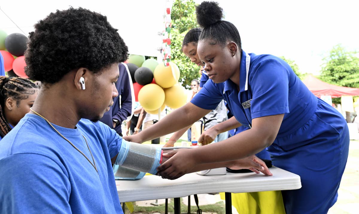 Nursing students Ashanti Mootie (right) check Tajay Fuller’s blood pressure during the College of Health Sciences’ annual health fair, held yesterday at UTech’s campus in St Andrew. 