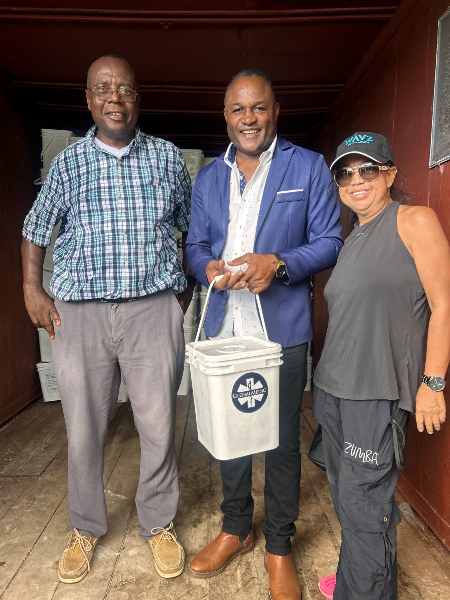 Wavz Beach proprietor Rosa Young (right), and health promotion officer Gerald Miller (left) hand over the food kits to Councillor Ian Myles during the distribution exercise at Wavz Beach, Negril.
