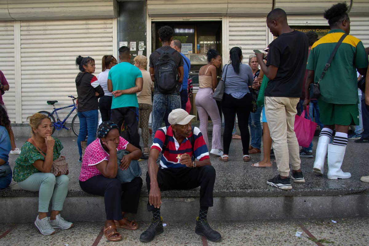 People wait their turn to enter a bank in Havana, Cuba.