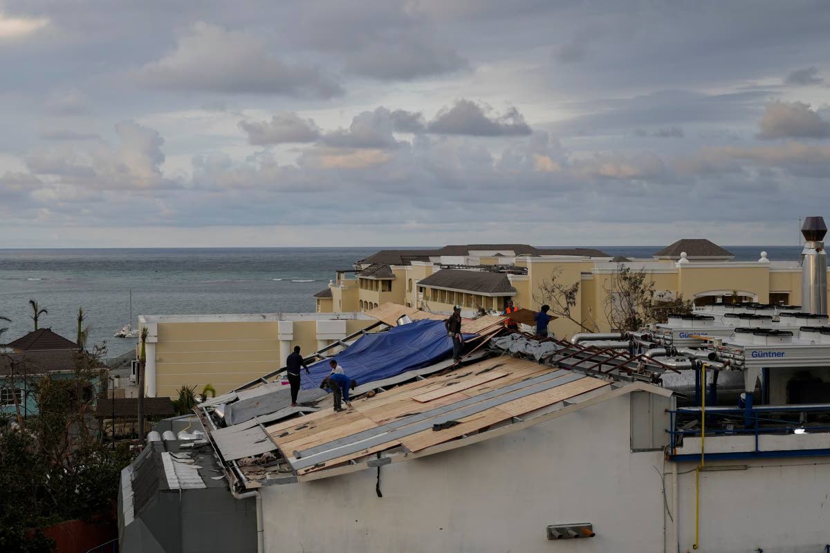 In this October 31, 2025, photo people are seen repairing the roof of a resort in Montego Bay, Jamaica, in the aftermath of Hurricane Melissa.