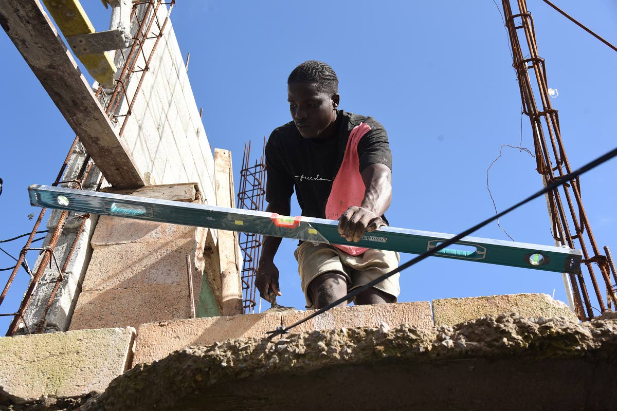 Matthew Piper checks that blocks laid are level while adding a room to a house for his family in Roaring River Steer Town, St Ann after their one room board house was extensively damaged during the passage of Hurricane Melissa in October 2025.