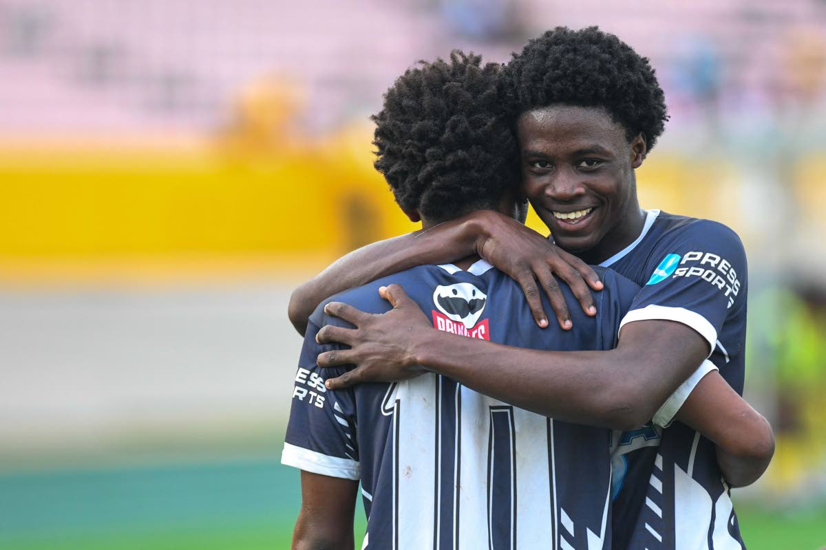 Jamaica College teammates Duwayne Burgher  (facing camera) congratulates goalscorer Jamone Lyle in a Manning Cup semi-final match in December 2024.