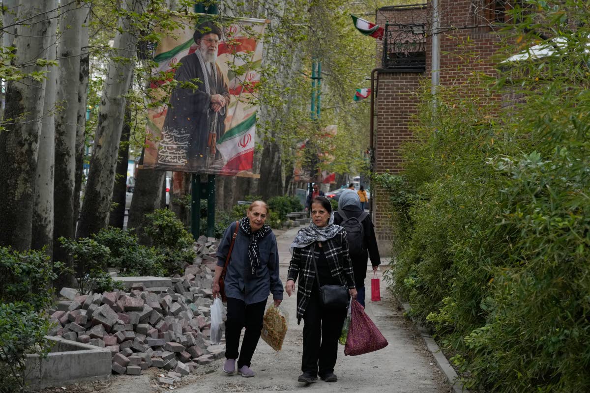 Women walk past a banner depicting the late Iranian Supreme Leader Ayatollah Ali Khamenei, who was killed in the U.S. and Israel strikes on February 28, in northern Tehran, Iran on April 12, 2026. (AP Photo/Vahid Salemi)