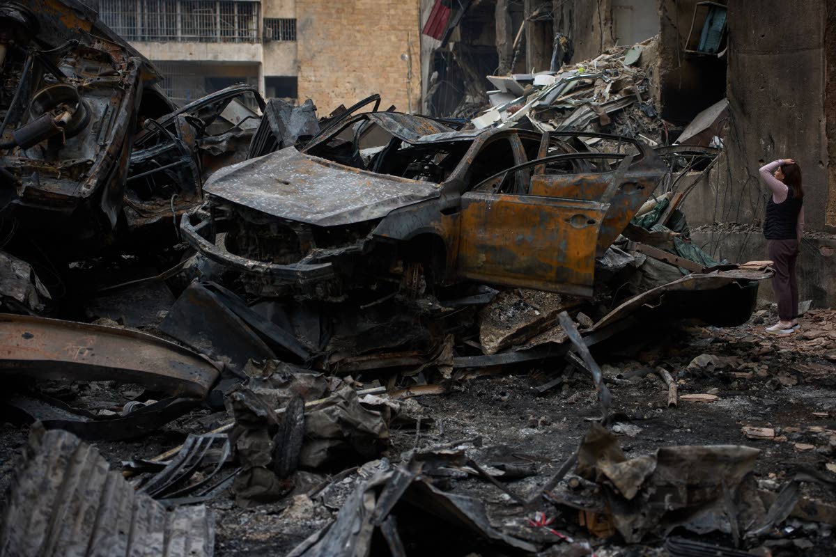 A resident checks damage to buildings as she walks near charred cars, at the site of Wednesday’s Israeli airstrike, in Beirut, Lebanon, on Friday.