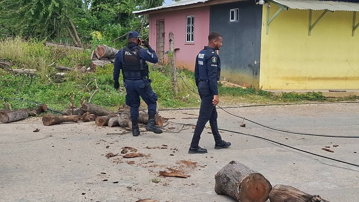 Members of the Jamaica Constabulary Force clear debris from the roadway during protest that disrupted traffic along the Hertford main road.