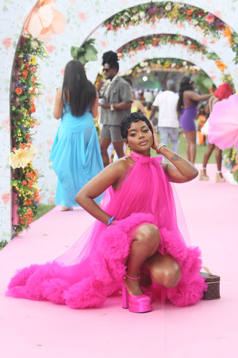 Influencer Richie-Ann Jackson Gabbidon commands attention in a vibrant pink mini with a dramatic train feathered detail.