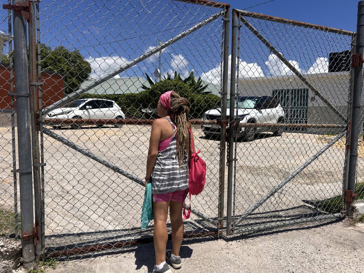 A frustrated woman stands at the locked gate of the Westmoreland courts office, seeking assistance after multiple unsuccessful visits. 