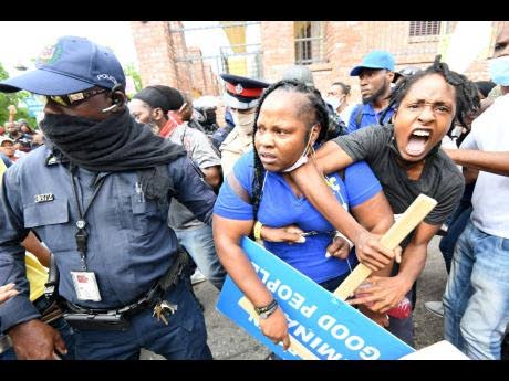 Police detain a protester during an unauthorised march in downtown Kingston on September 22, 2021. (Rudolph Brown photo)