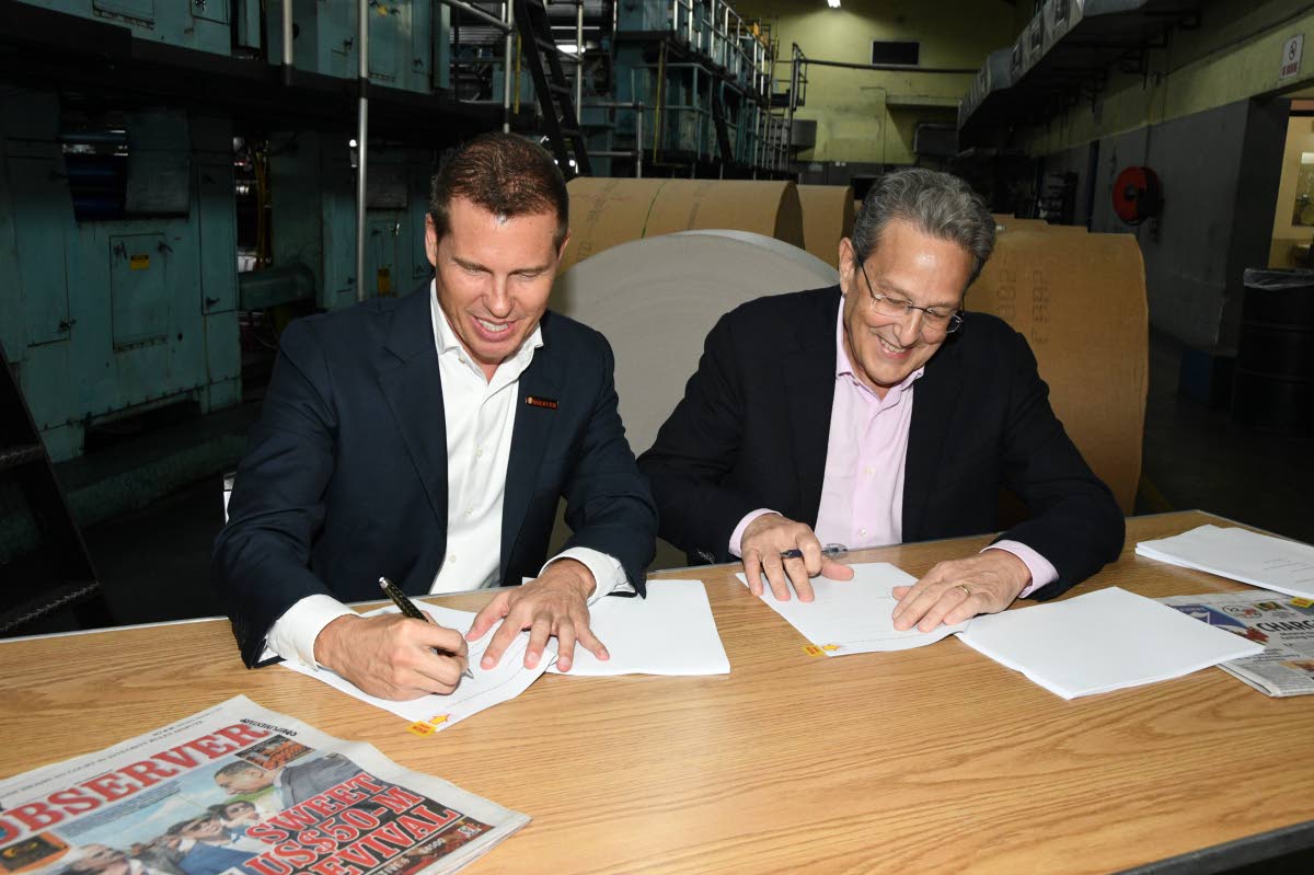 Executive Chairman of Jamaica Observer Limited Adam Stewart (left), and Chairman of RJRGLEANER Communications Group Joseph Matalon, sign the Joint Venture Agreement that set the foundation for the establishment of North Beech Limited – the new entity res