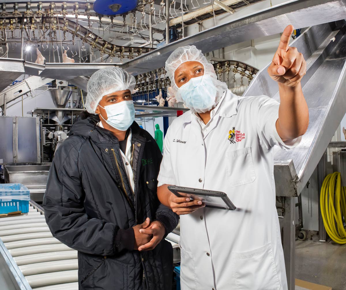 Chadwick Galloway (right), processing plant manager at The Best Dressed Chicken consults with Chad Joseph Francis, team leader/machine operator at the company’s facilties. 