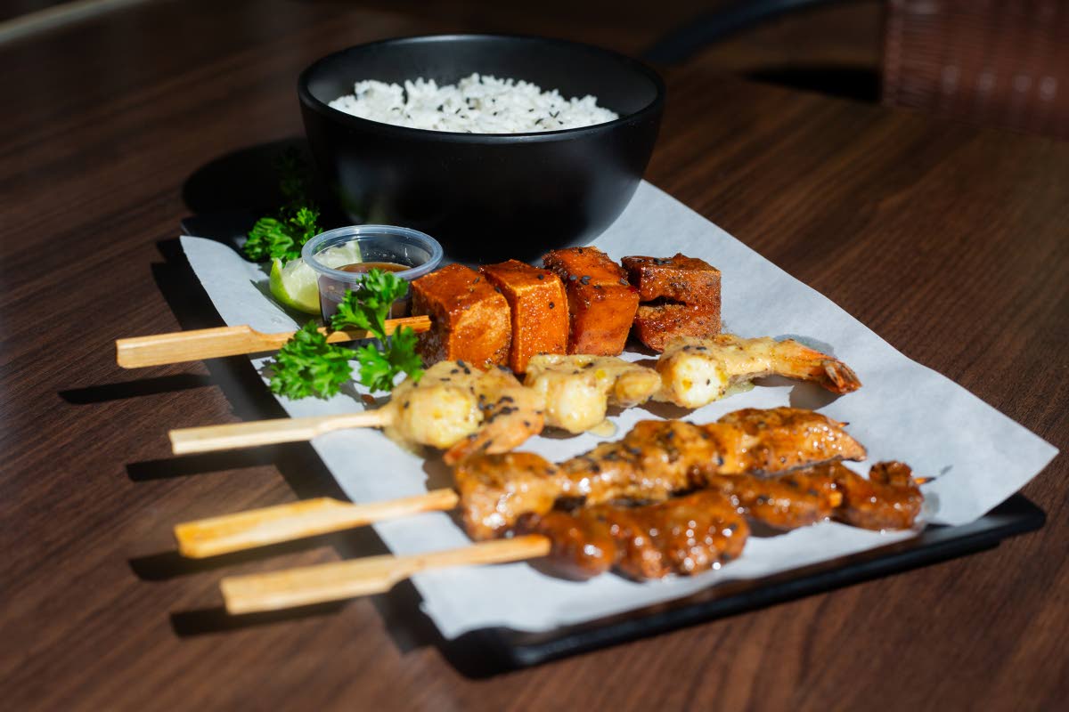 Quad skewers of shrimp, tofu, chicken and beef are served with a side of white rice.
