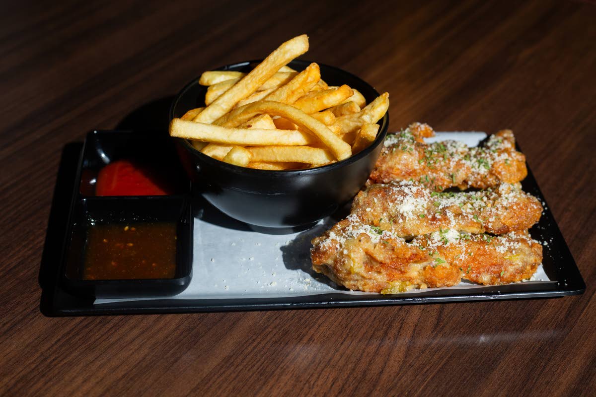 Bite into the garlic parmesan wings, served with a side of fries.