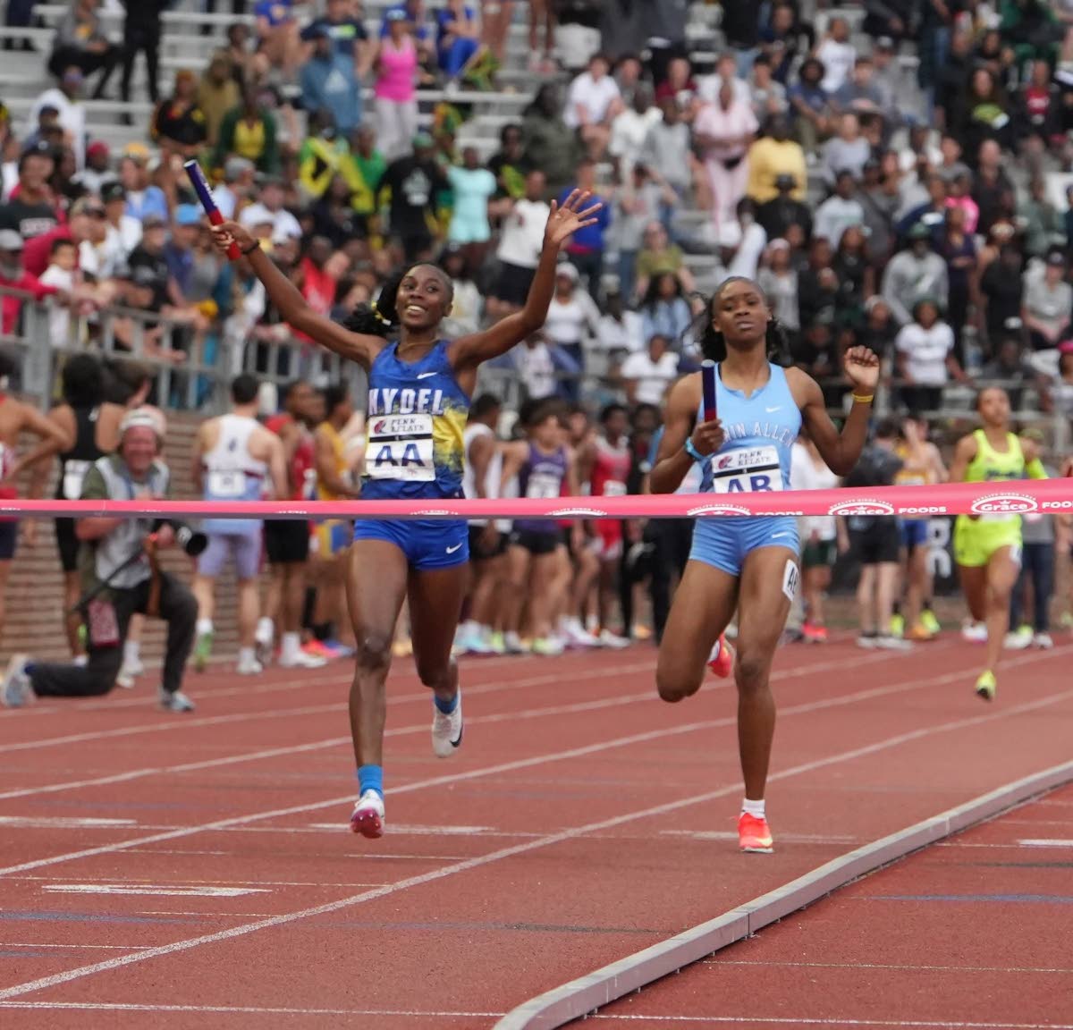 Hydel High’s Nastassia Fletcher (left) celebrates before crossing the finish line to seal her school’s fifth consecutive win in the Penn Relays Championship of America 4x400 metres in Philadelphia yesterday. At right is Edwin Allen High’s  Marria Cro