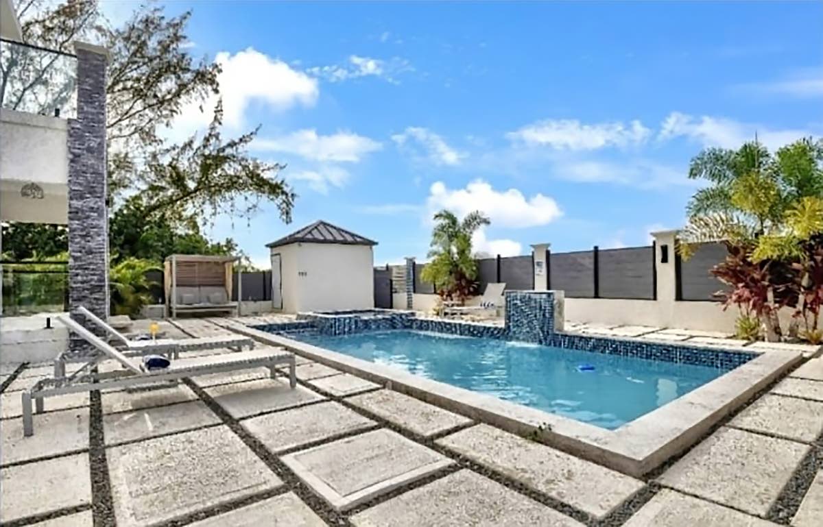 The backyard with a pool, hot tub, and waterfall, affording pleasure all year round.