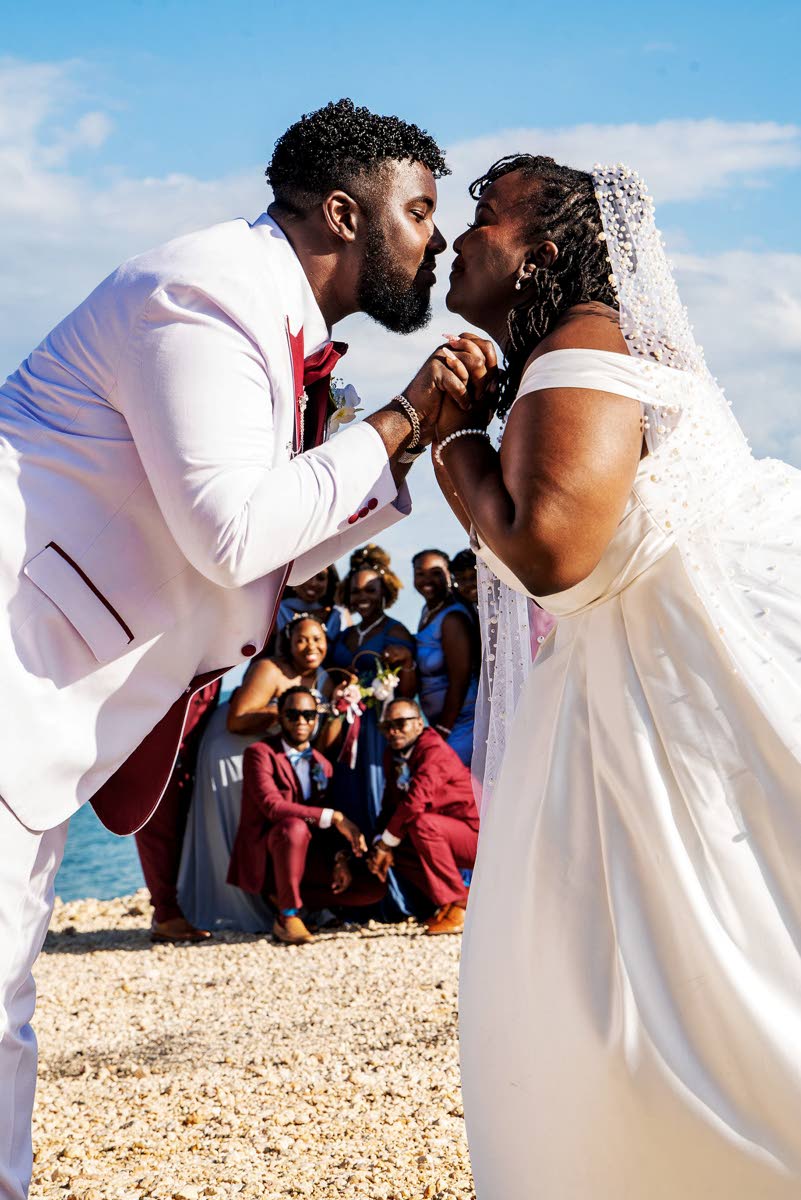 The newly married couple enjoy romantic bliss in full view of their wedding party.