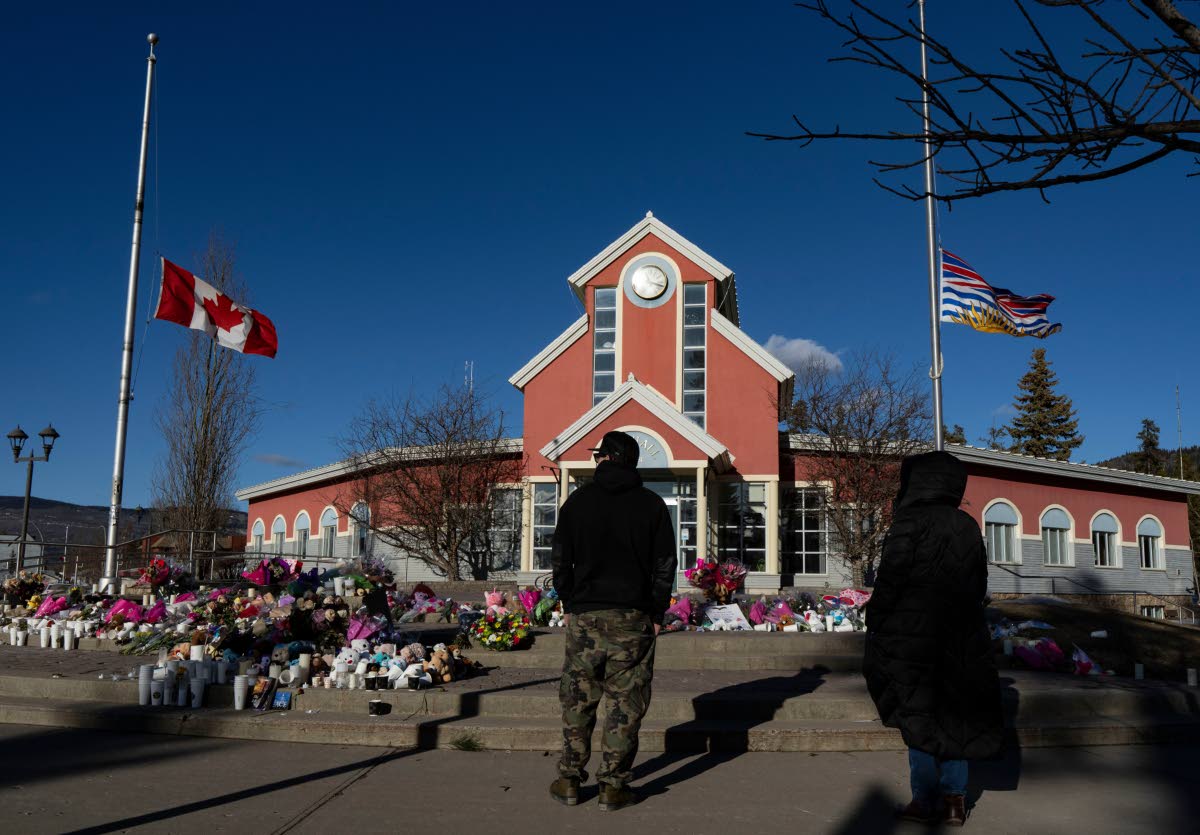  People pay their respects at a memorial on the steps of the Town Hall following a vigil the previous day in Tumbler Ridge, B.C., Saturday, February 14, 2026. (Christinne Muschi/The Canadian Press via AP, file)