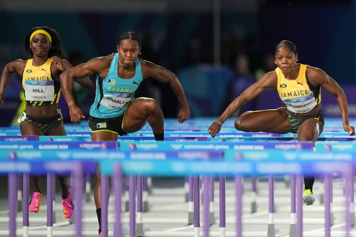 Jamaica’s Megan Simmonds (right) and Devynne Charlton of Bahamas (centre)  compete in the women’s 100m hurdles final at the Commonwealth Games in Glasgow, Scotland yesterday. Charlton won the event in 12.33  seconds with Simmonds second in 12.41. At le