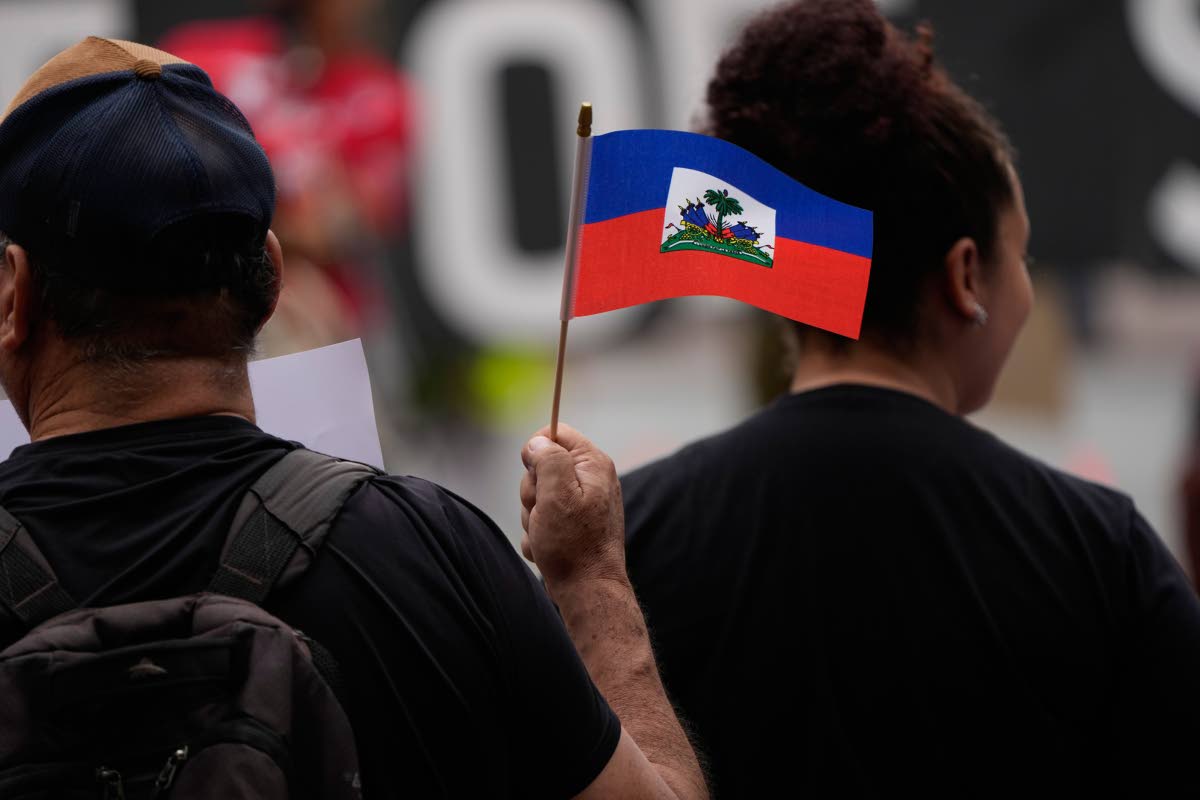 People hold Haitian flags and signs during a rally in support of immigrants living in the United States with temporary protected status, or TPS, on July 9, 2026, in San Diego.