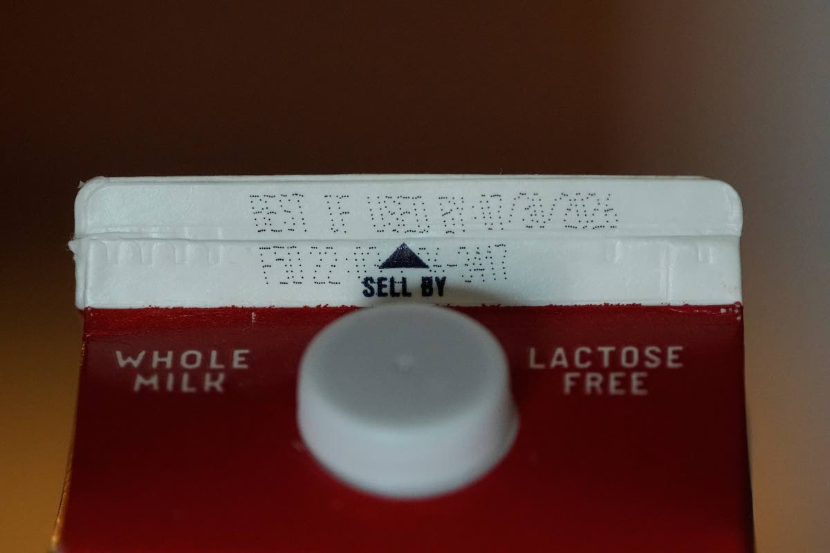 A Best If Used By date is stamped above a Sell By label on a milk carton.