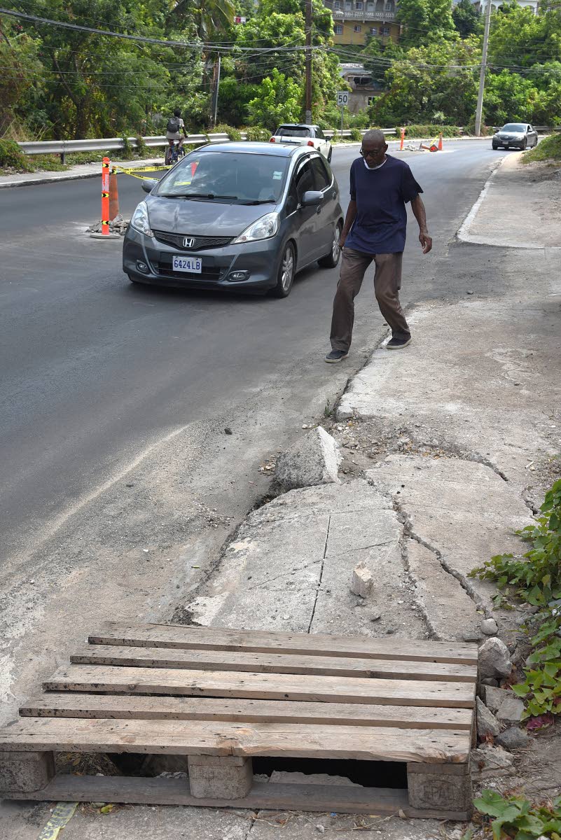 
A visually impaired man walks past a compromised section of a sidewalk along Munroe Road in St Andrew last week.