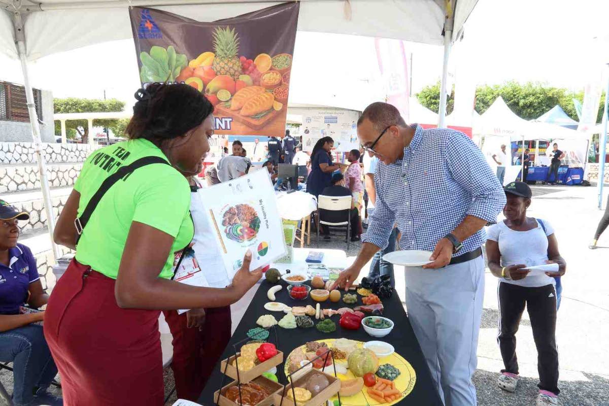 Dr. Christopher Tufton, minister of health and wellness, stops by the Kingston Public Hospital Dietetics Department booth and engages with a member of the team during the hospital’s 250th anniversary Health and Wellness Fair. 