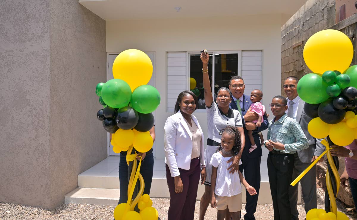 Prime Minister, Dr Andrew Holness (centre), looks on as New Social Housing Programme beneficiary Andrea Burke (second left) shows off the keys to her new home during the handover ceremony at 43 Rosemary Lane, Kingston on August 4. They are joined by (from 