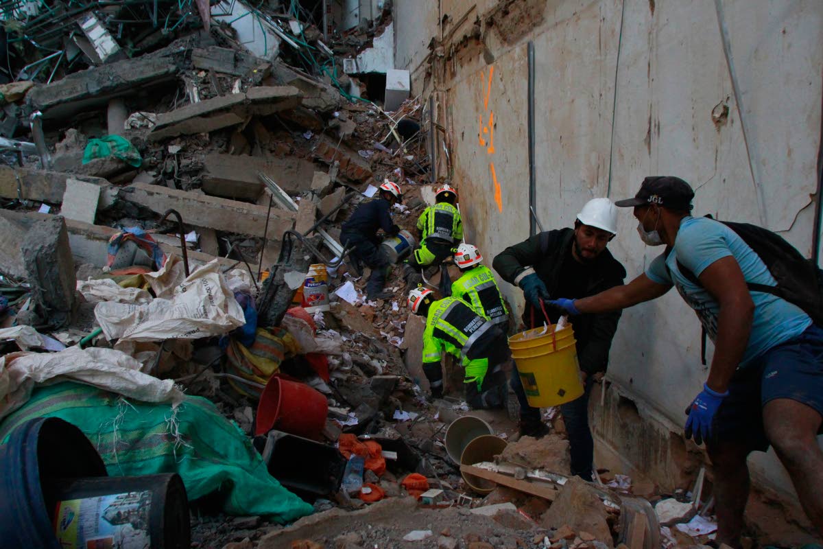Rescue workers and volunteers clear debris the day after an earthquake struck Pereira, Colombia, Tuesday, Aug. 11, 2026. (AP Photo/Miguel Angel Lopez)