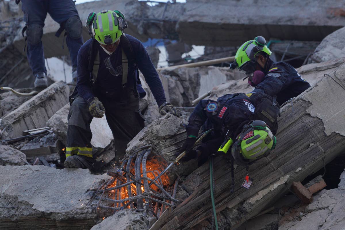 Rescue workers cut through debris as they search for survivors the day after an earthquake struck Cali, Colombia, Tuesday, Aug. 11, 2026. (AP Photo/Ivan Valencia)