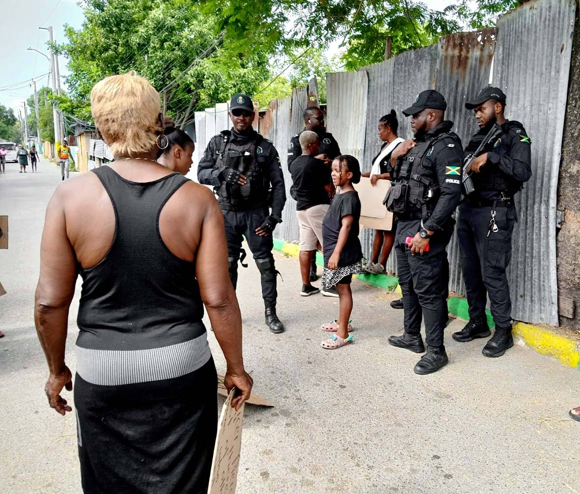 Police officers in Central Village on Monday during a protest demanding justice for the murder of resident Shemane Nugent.