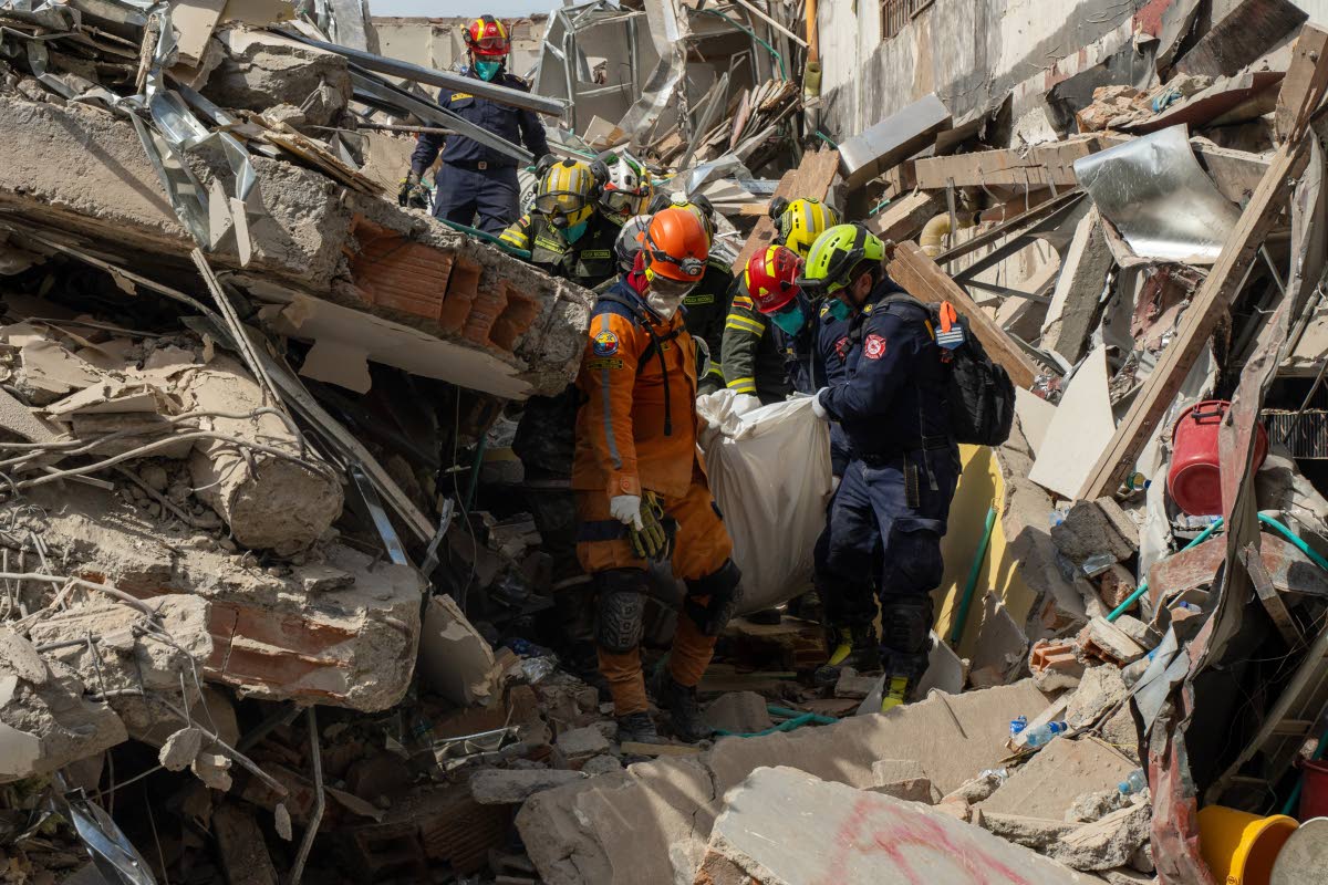 Rescuers carry the body of a victim from the rubble four days after an earthquake hit Pereira, Colombia.