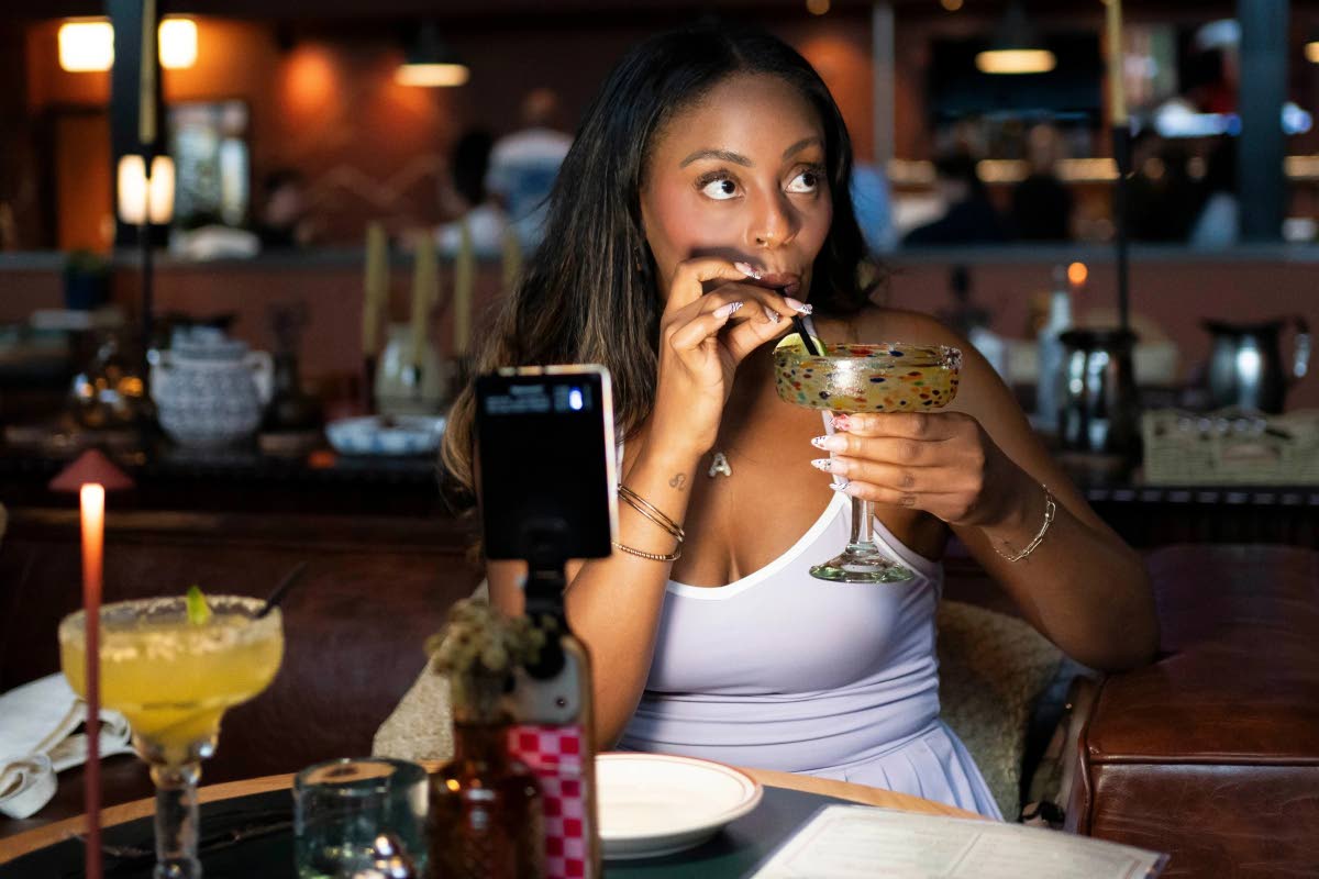Phoenix-based content creator Aiesha Beasley films herself as she samples a margarita during the grand opening of Padeland, a venue for the racket sport padel in Chandler, Arizona, August 13. 
