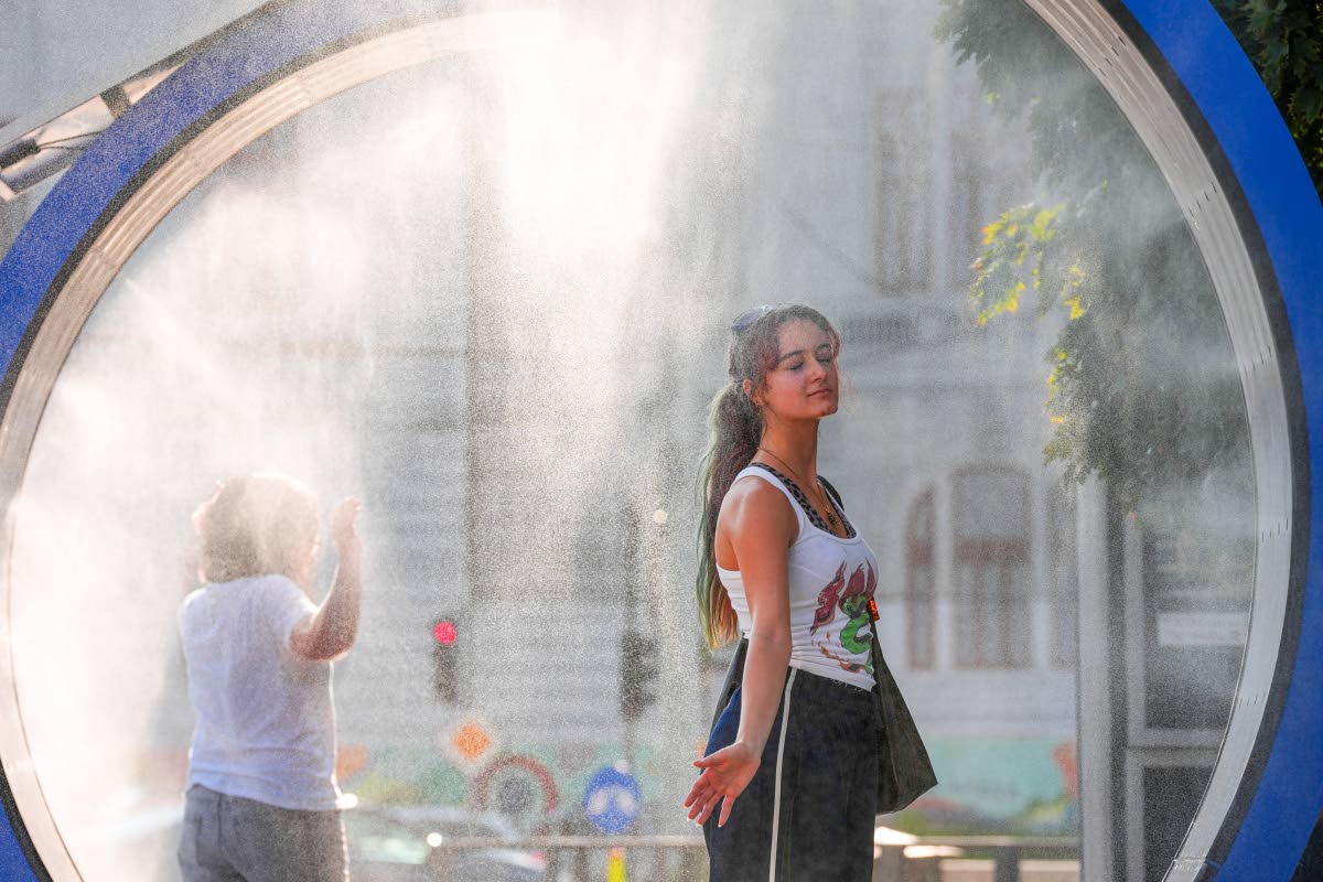  A woman pauses while she walks through a water mist machine installed by city administration to assist people in coping with the heat in Bucharest, Romania, on August 6.