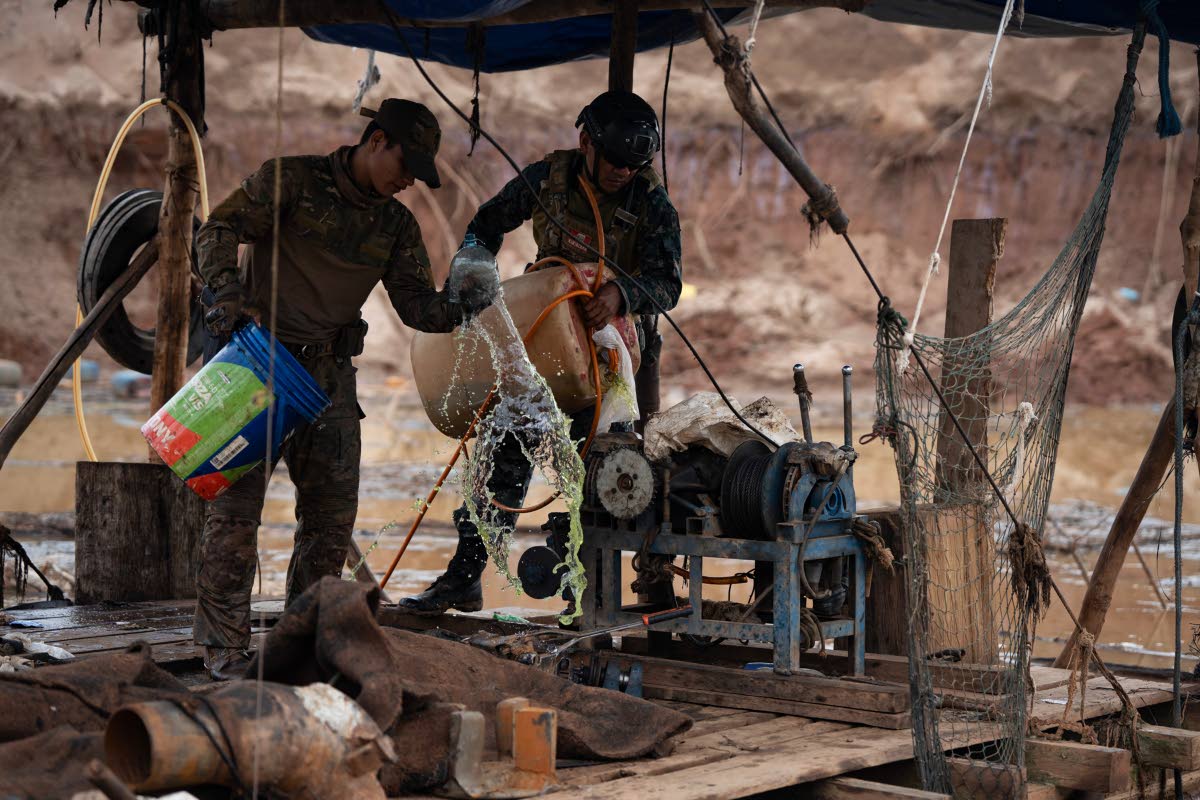 Peruvian Navy soldiers pour gasoline onto a dredge during an operation to combat illegal mining.