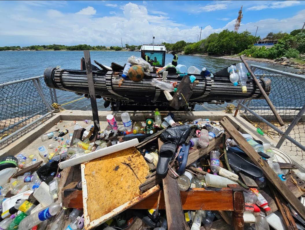 Extracting debris from an interceptor barrier designed to prevent waste from entering the Caribbean Sea.