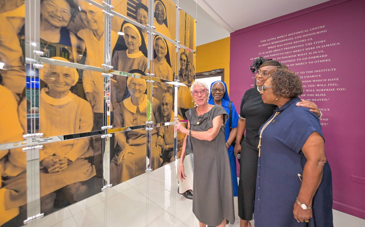 Minister of Culture, Gender, Entertainment and Sport, Olivia Grange (right), and Speaker of the House of Representatives, Juliet Holness (second right), join Sister Shirley Chung (left) as she points to herself in a picture taken in 2004 of a group of 30 S
