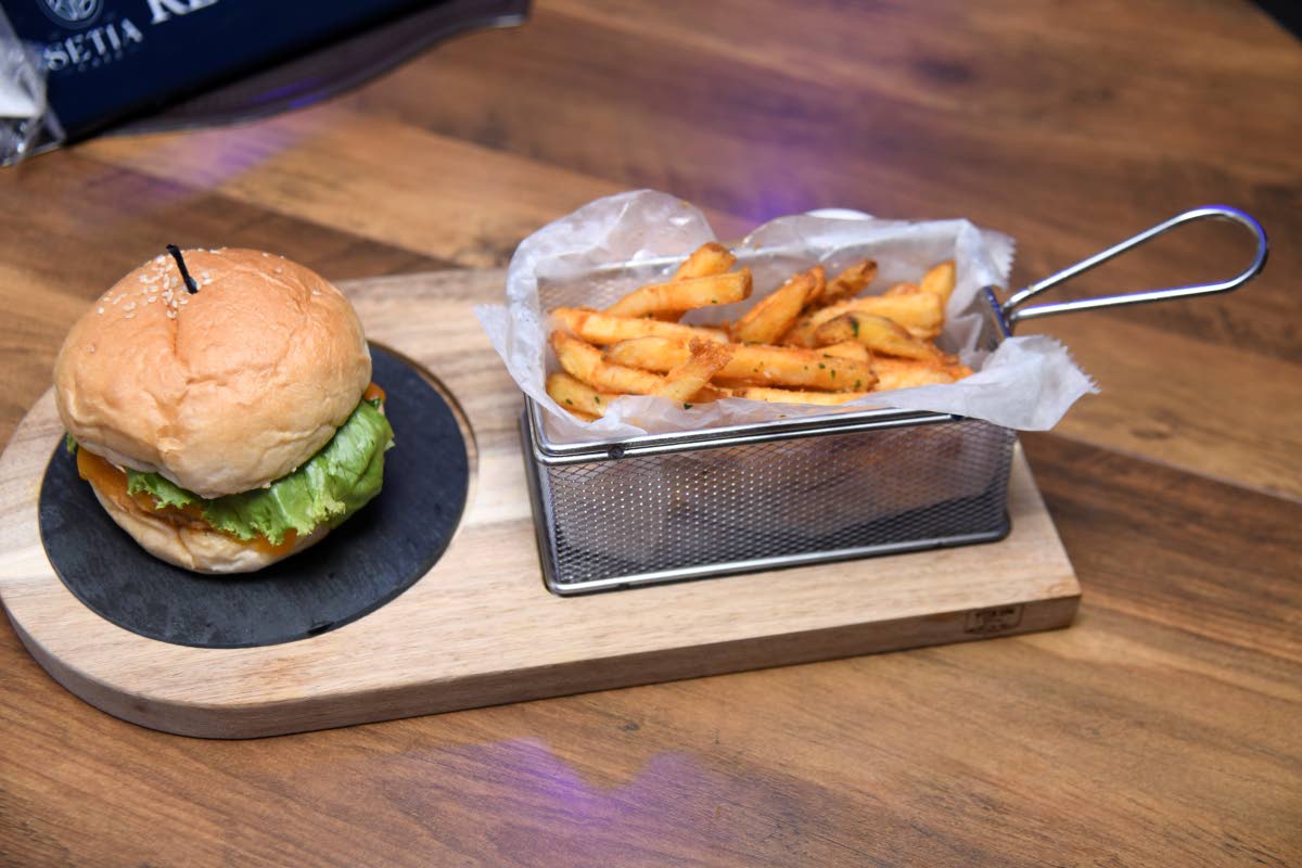 The jerk chicken burger is served with a side of fries.