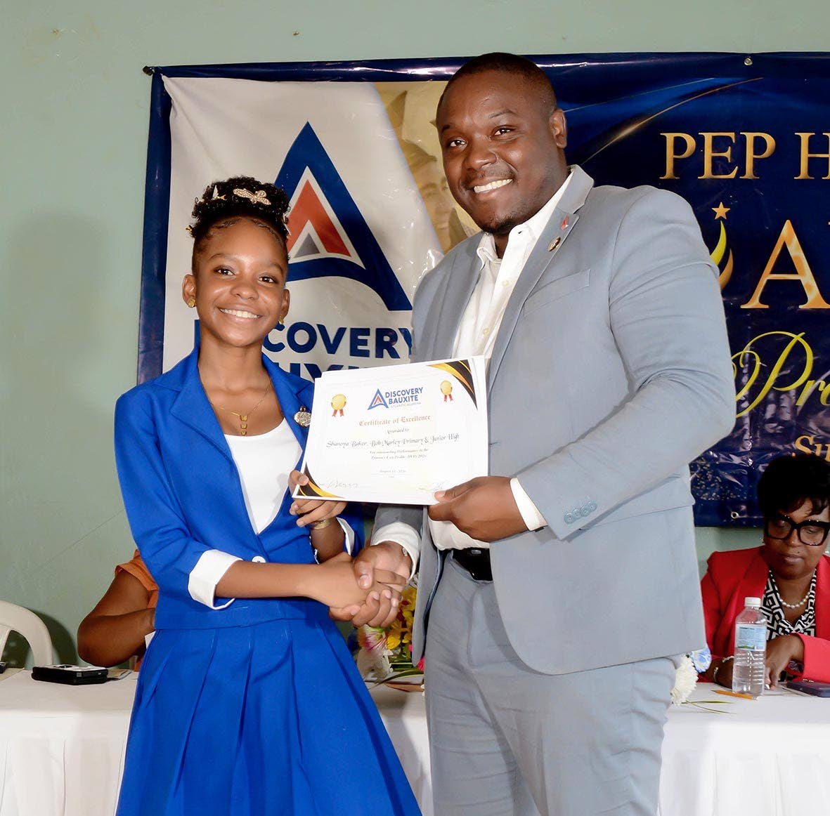 Guest speaker Dr Daren Johnson presents Shanoya Baker of Bob Marley Primary School with her award.