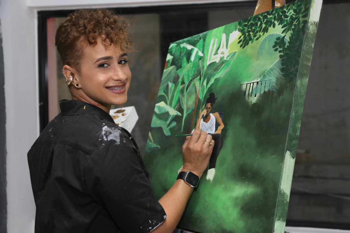 Artist Simone Racquel pauses for a snap while completing her live event painting of D’Yani’s ‘LLAP – Live Life & Prosper’ album cover, making her painted overalls look totally chic. 