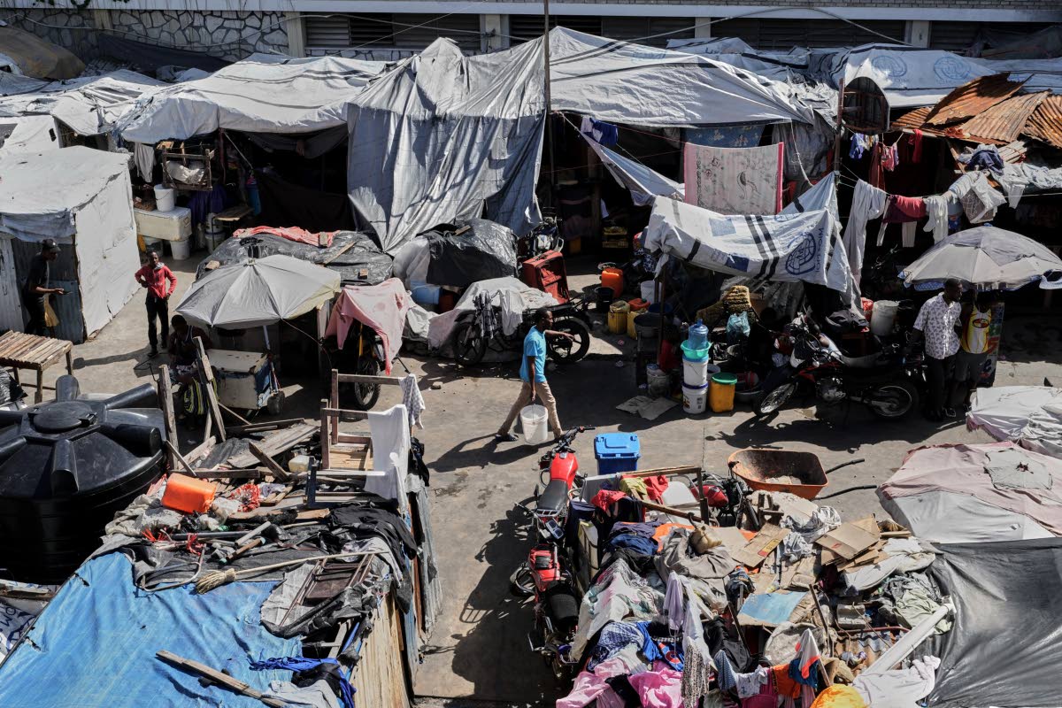 A man carries a buckets of water where families displaced by gang violence are living in Port-au-Prince, Haiti.