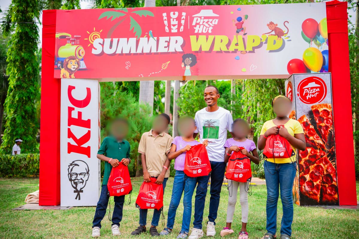Kemar Moodie, facility manager at Reddies Place of Safety, joins children from the home after they received back-to-school supplies from KFC and Pizza Hut.
