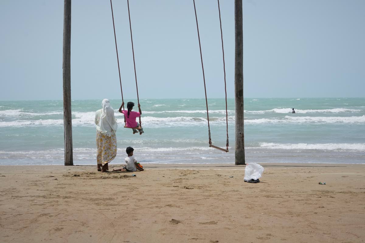 A woman pushes a girl on a swing on a beach along the Strait of Hormuz in Kuhestak, Iran.