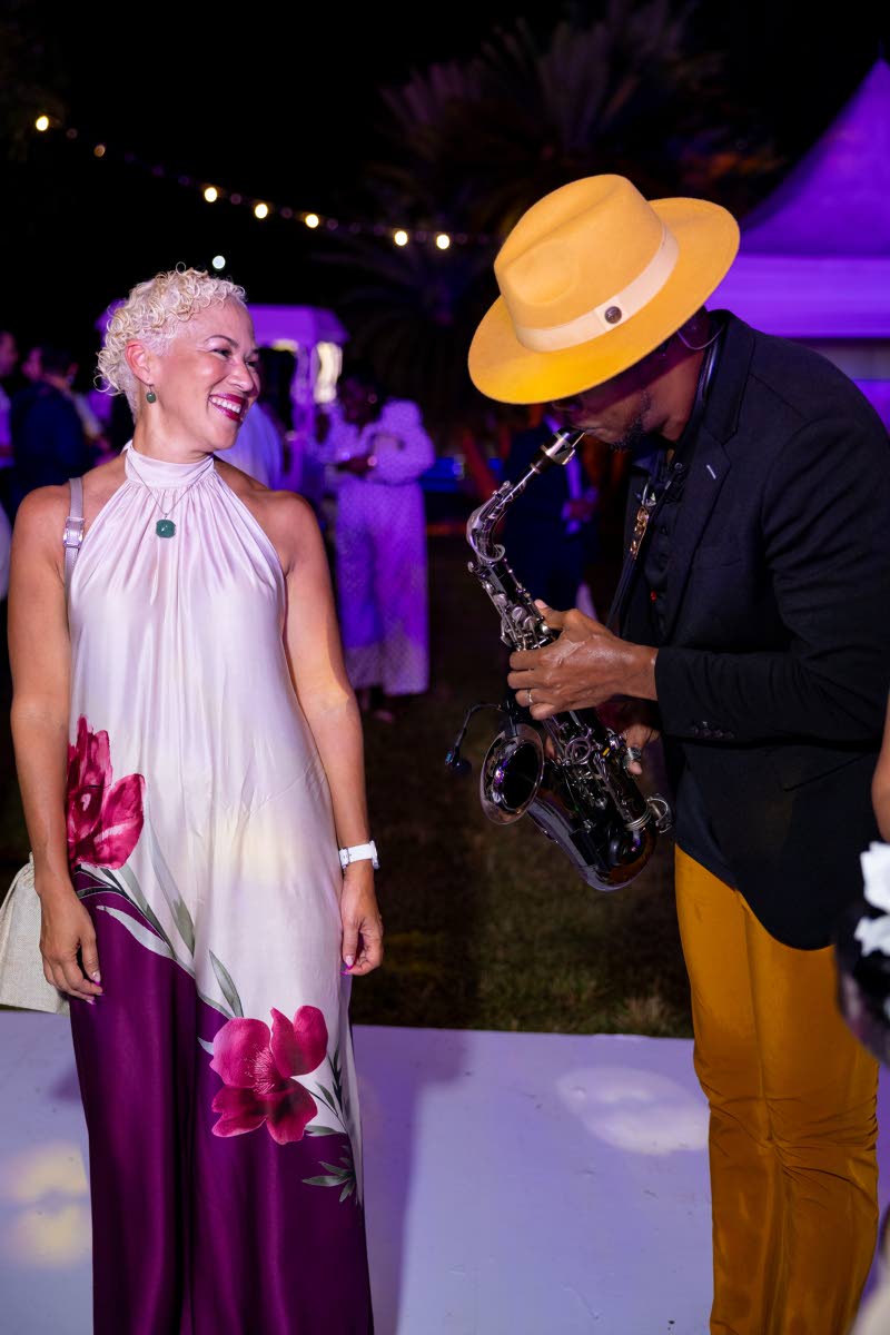 Guardian Group Chief Operating Officer Greer Quan looks elegant in a flowing white halter-neck maxi as saxophonist Verlando Small serenades her.