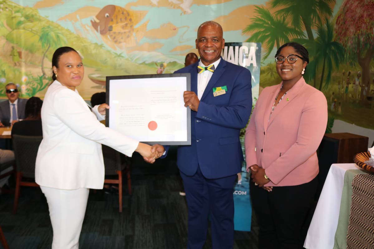 Lishann Salmon, chargé d’affaires at the Embassy of Jamaica, formally presents Jamaica’s honorary consul to Richmond, Lieutenant Karl M. Bryan, with his writ of commission during his installation ceremony at Carena’s Jamaican Grill in Richmond on Su