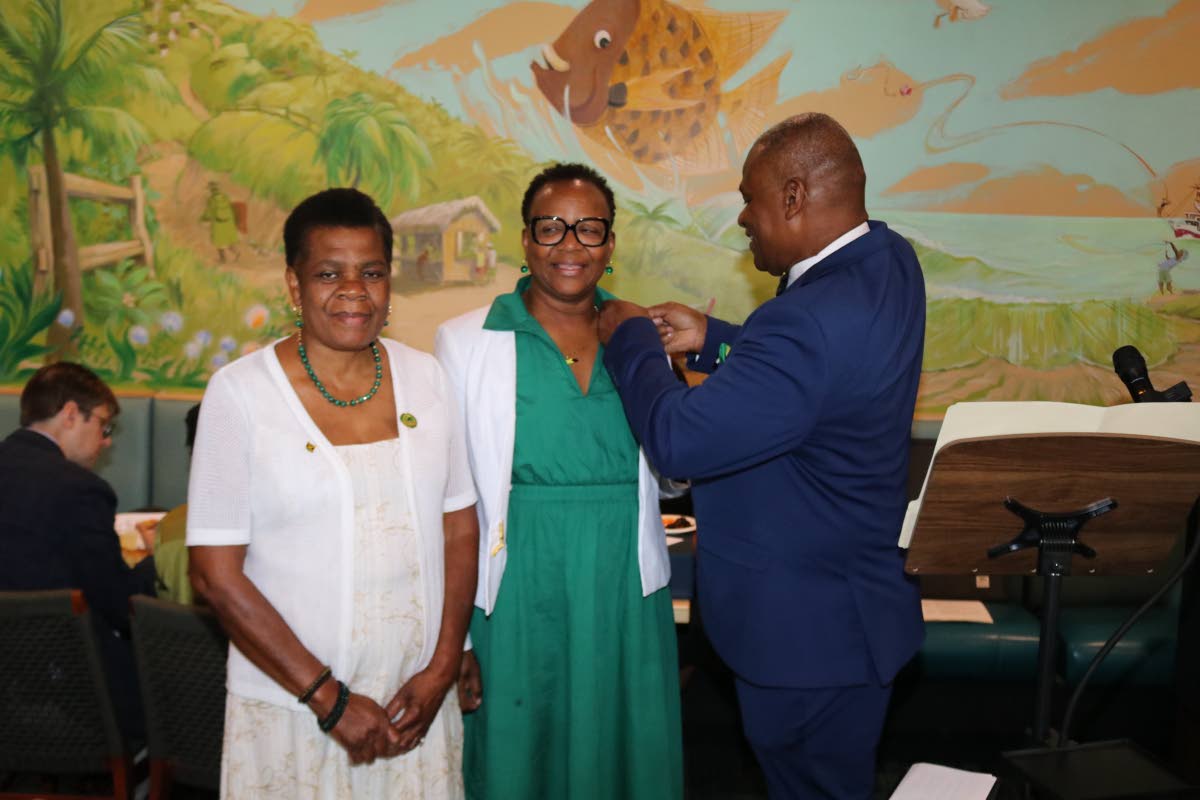 Jamaica’s Honorary Consul to Richmond, Lieutenant Karl M. Bryan, right  preforms his first official duty by pinning President of the  Association of Jamaicans in Richmond (AJR  Esther Lawe) (AJR) Treasurer Eunic Green The occasion was the installation ce
