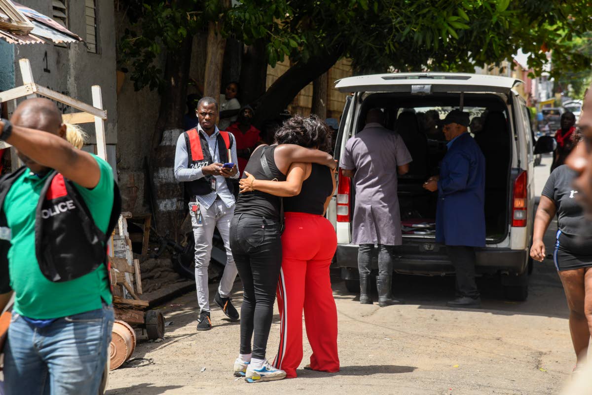 
Funeral home attendants put the bodies of seven-year-old Keriecia Hutchinson and her four-year-old brother, Samson Cameron, in their vehicle along Smith Lane in downtown Kingston yesterday after the two children died in a house fire. 